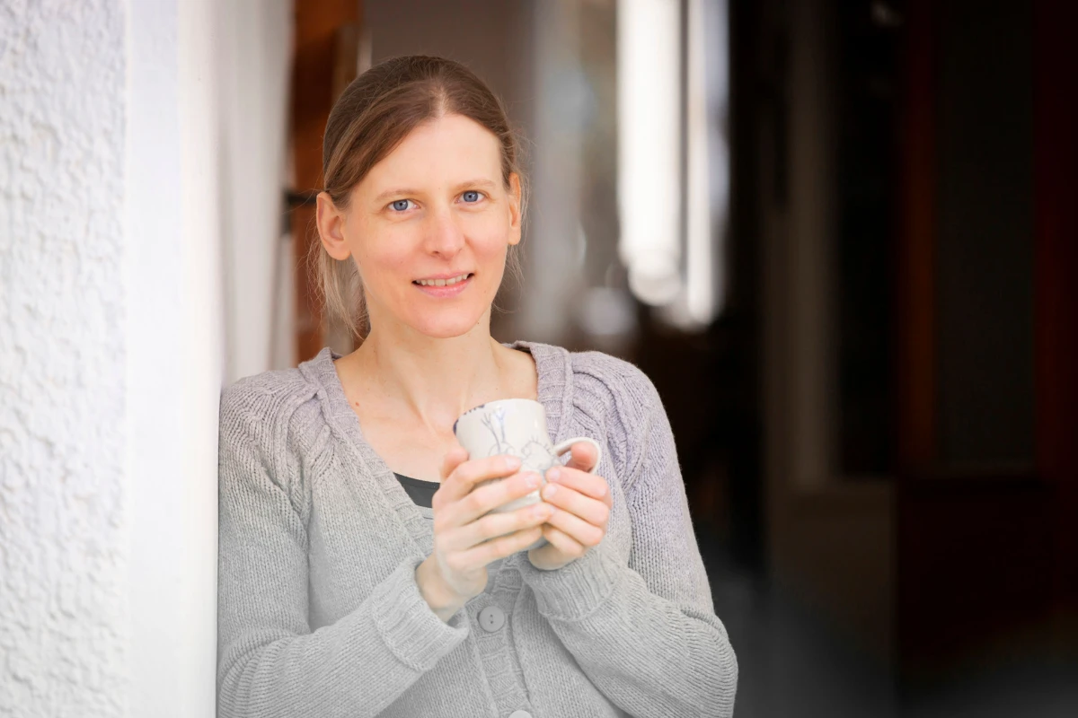 Frau mit Tasse in der Hand an der Wand